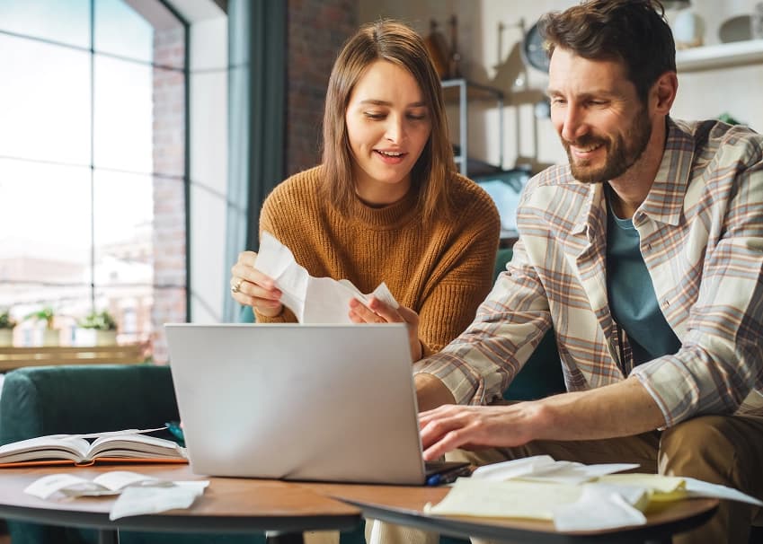 Couple reviewing finances and mortgage loan documents together on a laptop