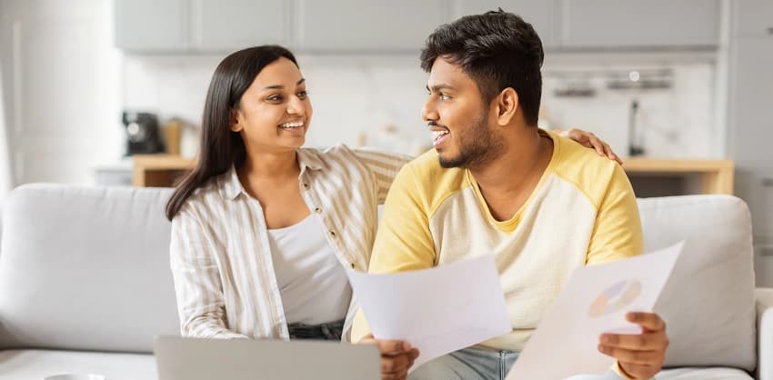Couple reviewing mortgage loan documents together on a couch at home