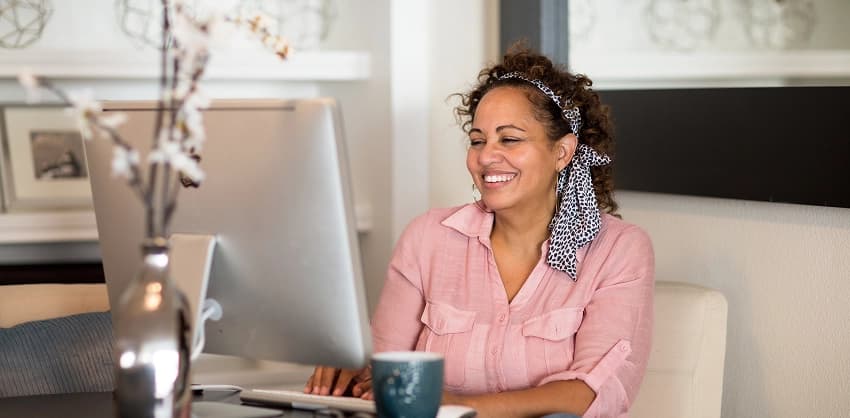 Smiling woman working on a laptop at home, enjoying online banking services