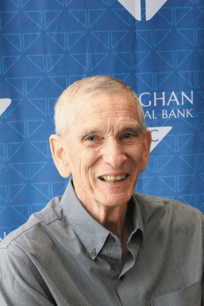 Smiling man in a gray shirt posed in front of a Croghan Colonial Bank backdrop