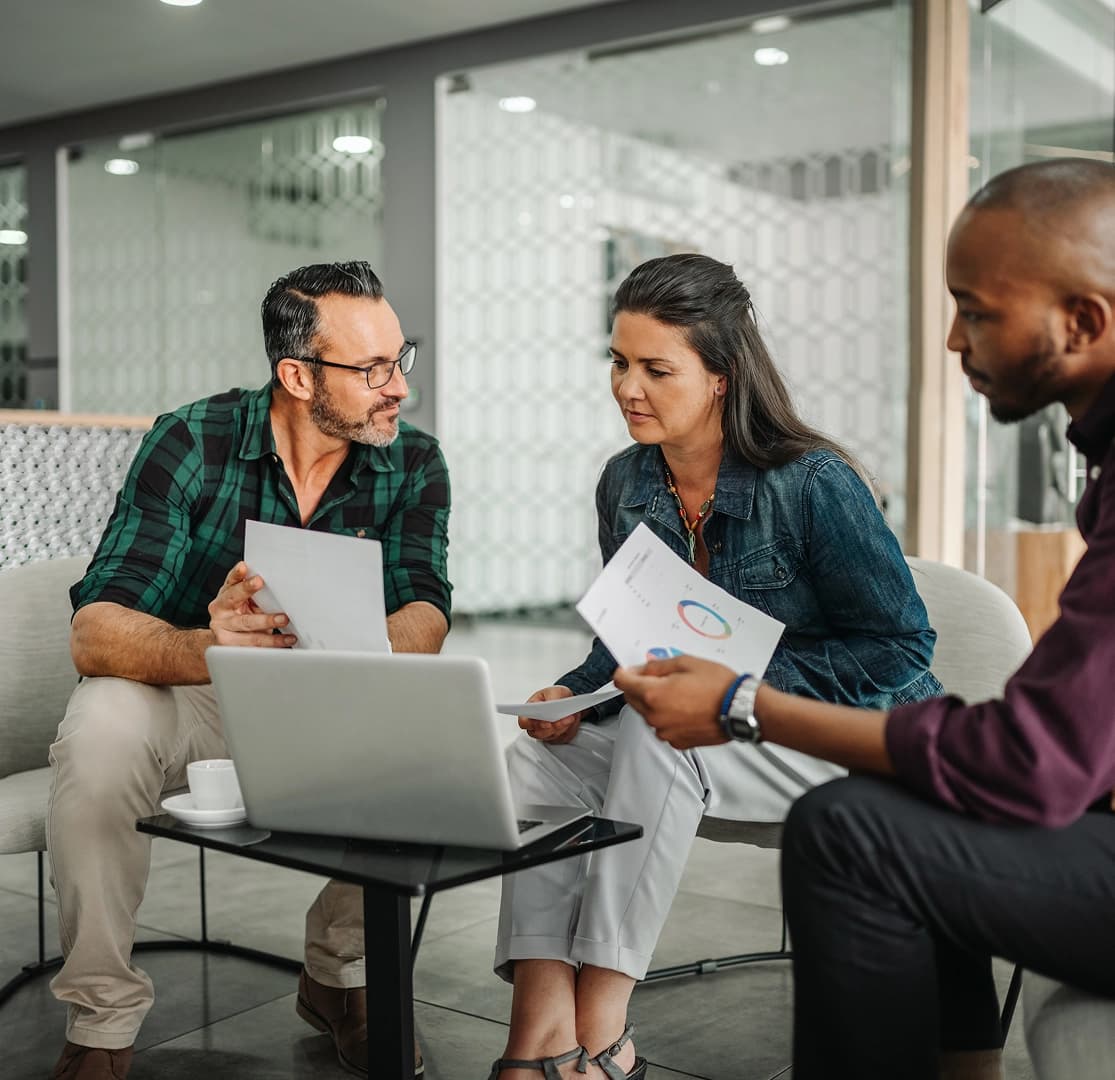 Three colleagues reviewing financial charts and documents during a business meeting.
