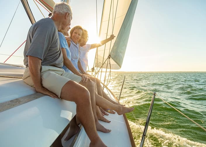 Couple enjoying retirement on a sailboat at sunset after successful retirement planning