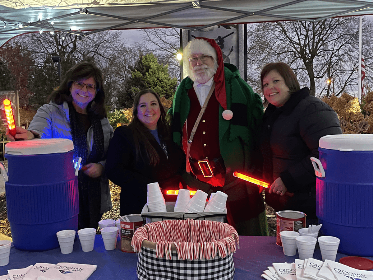 Croghan Colonial Bank volunteers and Santa Claus serving hot cocoa and candy canes at outdoor holiday event