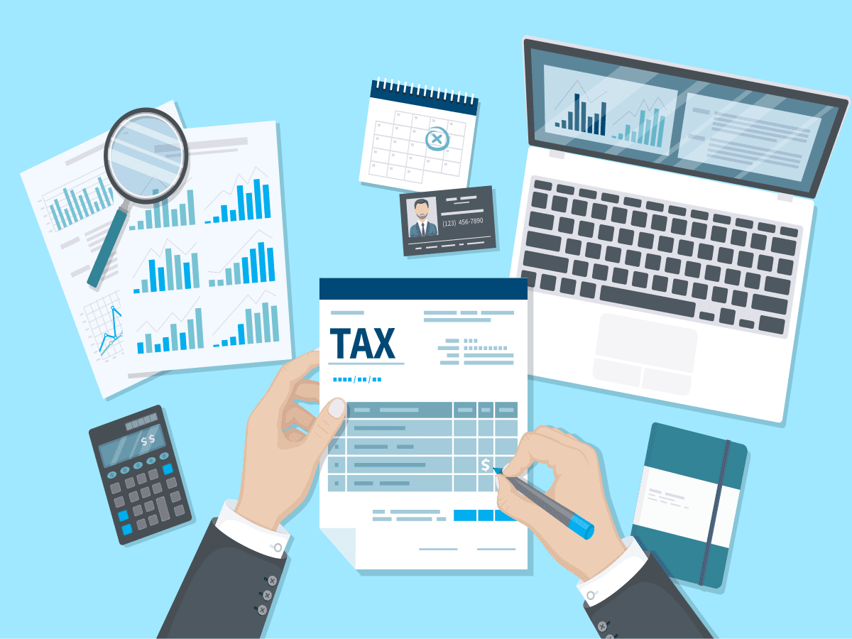 Hands completing a tax form surrounded by financial charts, calculator, and laptop for financial planning