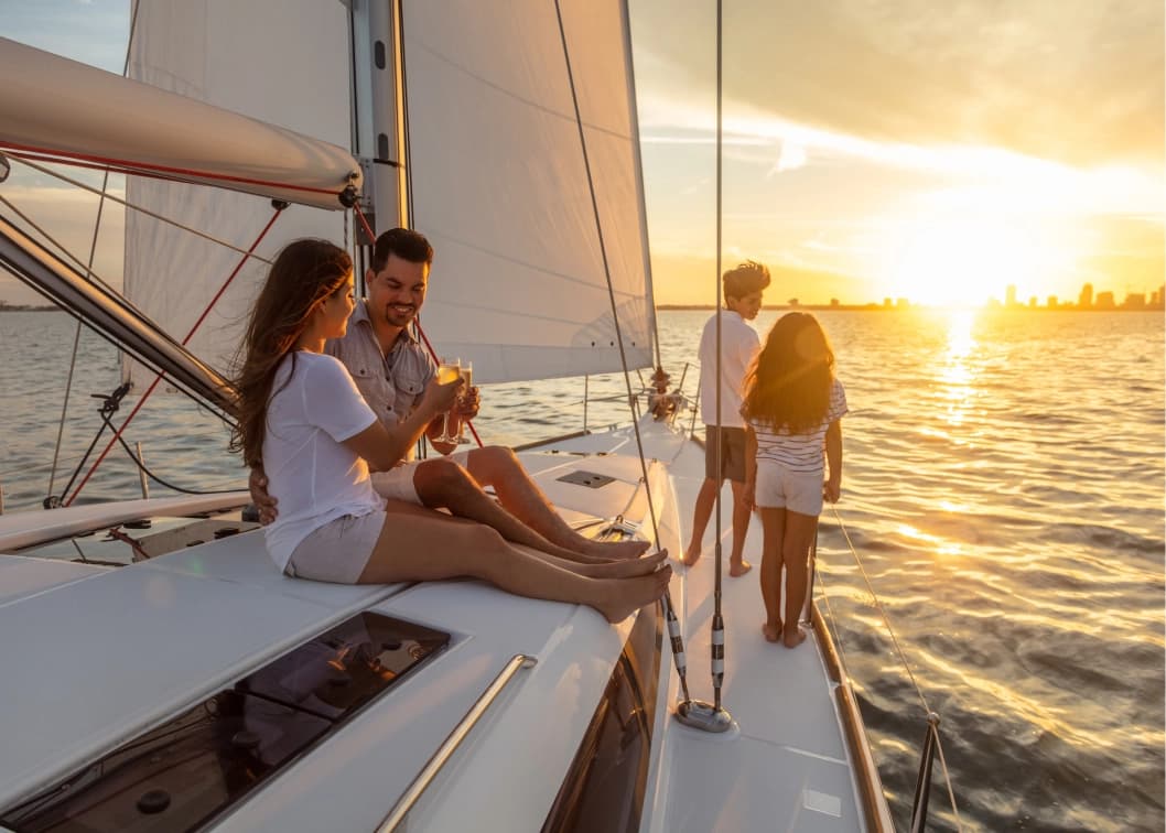 Family relaxing on a sailboat deck with champagne at sunset