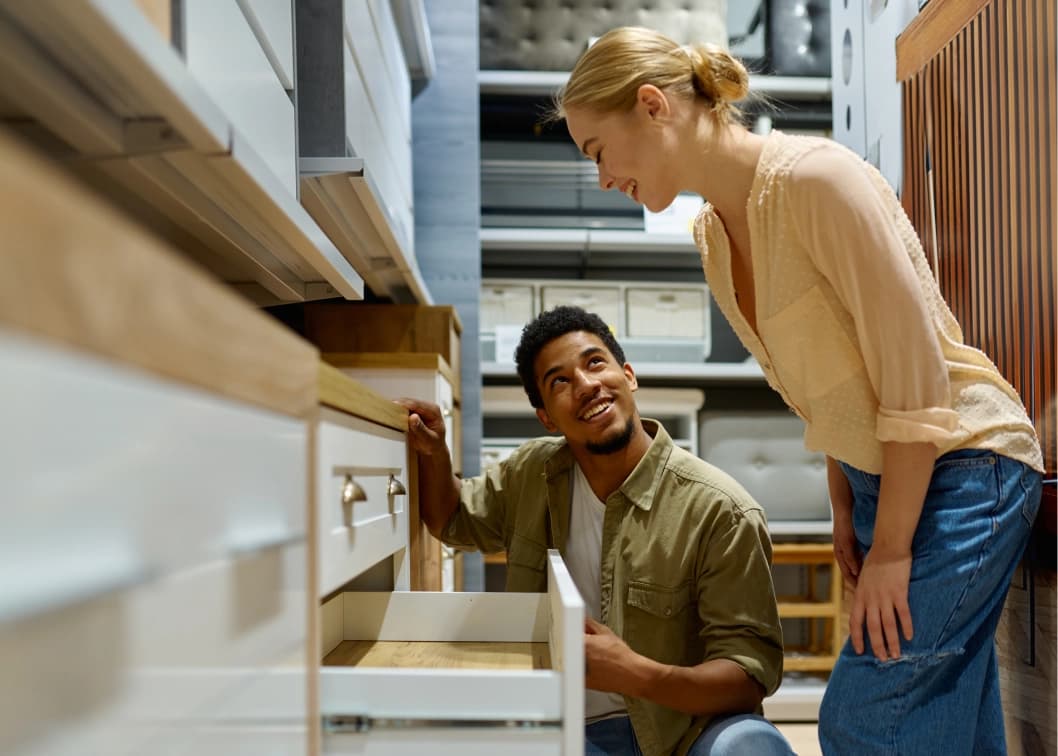 Couple smiling while examining furniture drawers in a home goods store