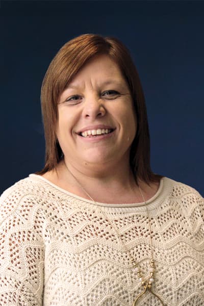 Smiling Croghan Bank employee with reddish-brown hair wearing a cream knit sweater