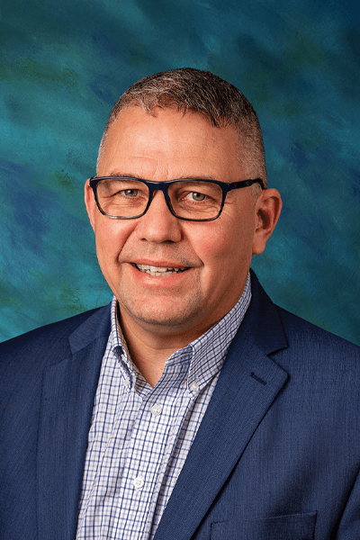 Smiling Croghan Bank team member wearing glasses and a blue blazer with a plaid shirt