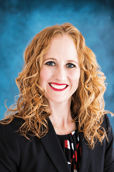 Smiling Croghan Bank woman with curly hair in a black blazer against a blue background