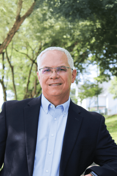 Smiling Croghan Bank professional wearing glasses in a dark blazer among trees