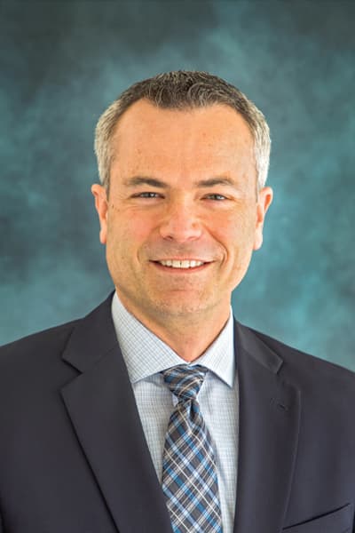 Croghan Bank professional smiling in a dark suit and plaid tie