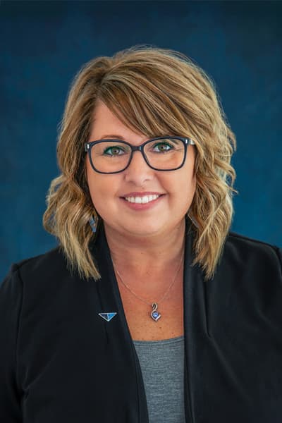 Smiling Croghan Bank employee with blonde hair and glasses wearing a black blazer with a blue lapel pin