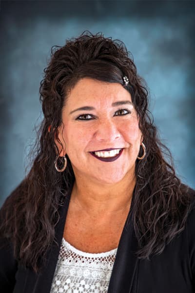 Smiling Croghan Bank female staff member with dark curly hair wearing a black blazer and white top