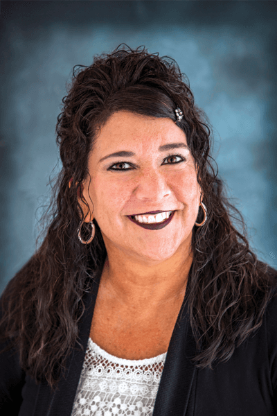 Smiling Croghan Bank female staff member with dark curly hair wearing a black blazer and white top