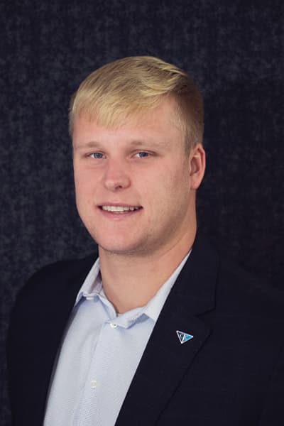 Smiling young man with blonde hair in a navy blazer with a Croghan Bank pin