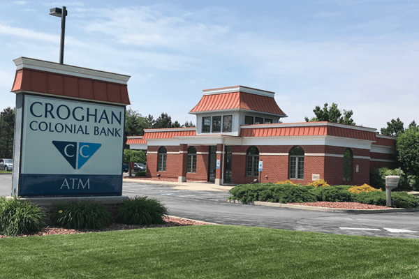 Croghan Colonial Bank branch exterior with ATM sign, brick building, red roof, and landscaped parking lot