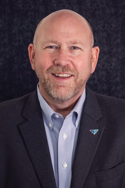 Smiling Croghan Bank professional in a dark blazer with a blue shirt and company pin
