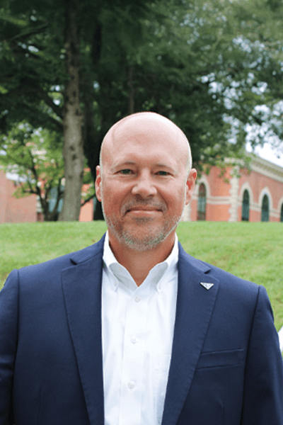 Croghan Bank professional with a beard in a navy blazer smiling outdoors near a brick building