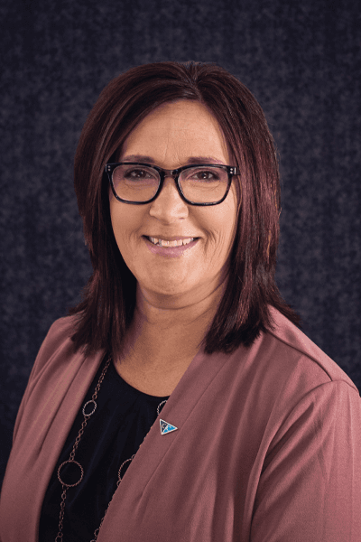 Smiling Croghan Bank female staff member with dark hair and glasses wearing a mauve blazer