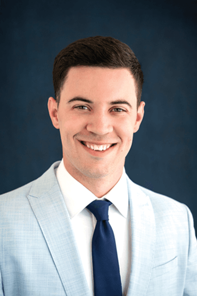 Smiling young man in a light gray suit with a navy tie