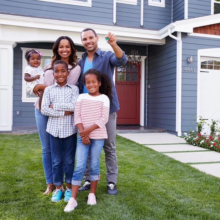 Happy family holding house keys in front of their new home