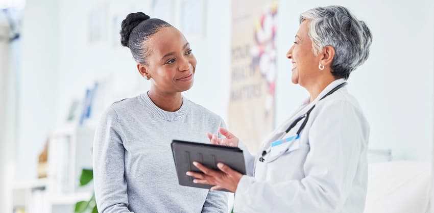 A patient smiling while consulting with her doctor during a health savings account or wellness visit discussion.