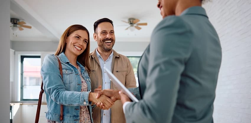 Couple shaking hands with a real estate agent after finalizing a home loan
