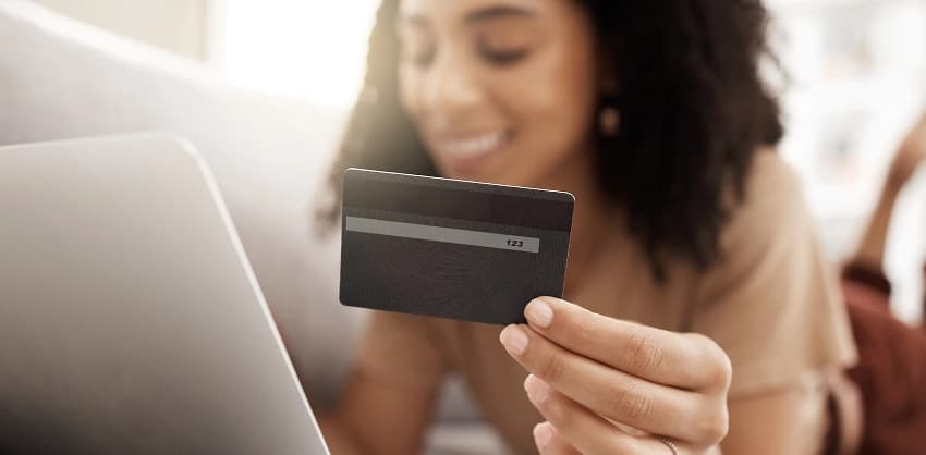 Woman holding a credit card while using a laptop for online banking or payments