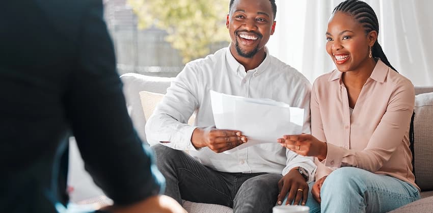 Joyful couple receiving documents from a financial advisor, possibly reviewing personal or home loan details