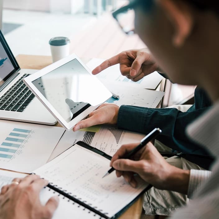 Two professionals reviewing financial charts and data on a tablet for investment management
