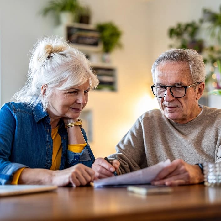 Couple reviewing financial documents together at a home table, discussing retirement planning or mortgage loan options