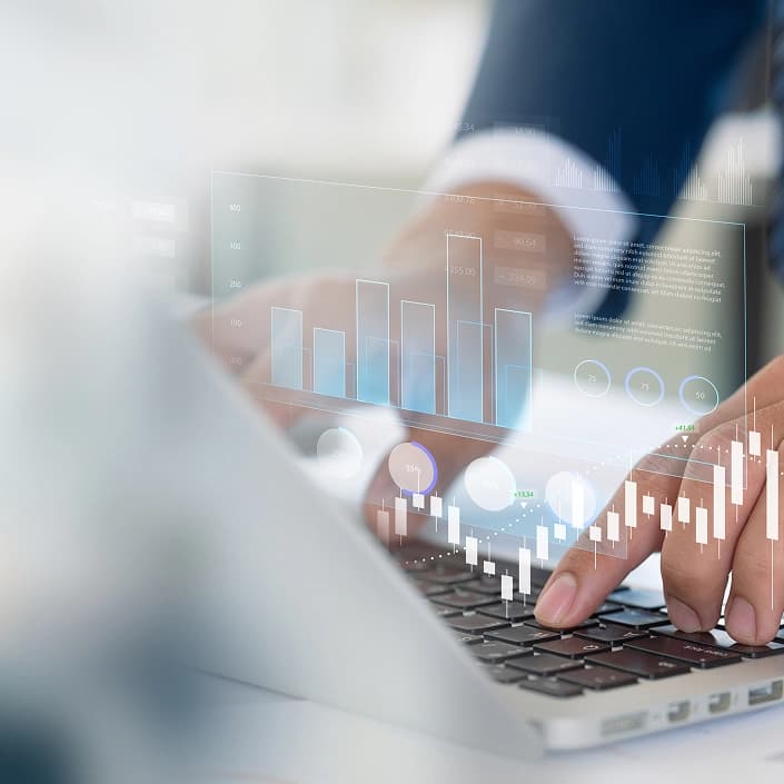 Person typing on laptop with holographic financial charts and investment data displayed