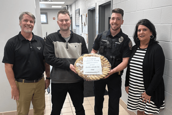 Croghan Colonial Bank staff presenting a cookie wreath to a local police officer