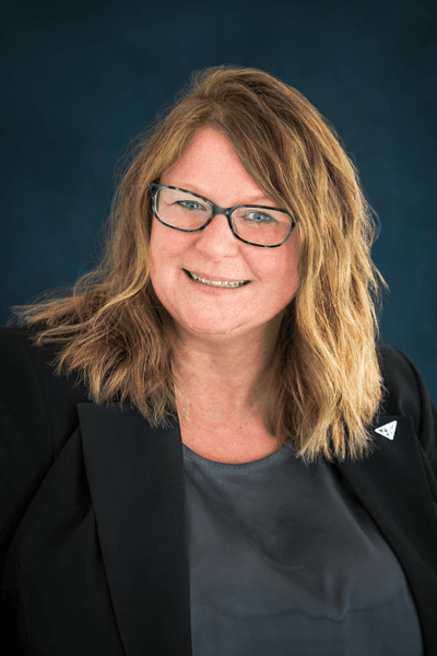 Smiling Croghan Bank female staff member with blonde hair and glasses wearing a black blazer
