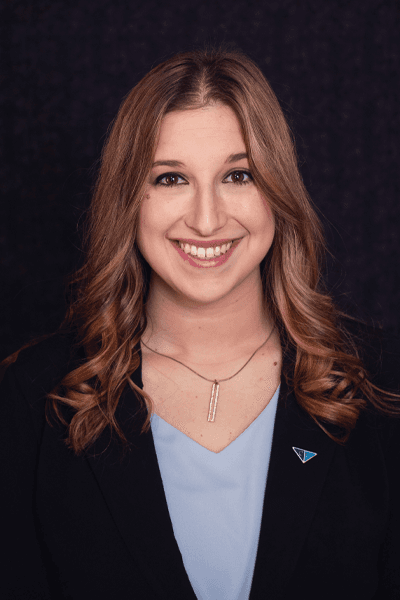 Smiling Croghan Bank team member with long wavy hair wearing a black blazer and light blue top