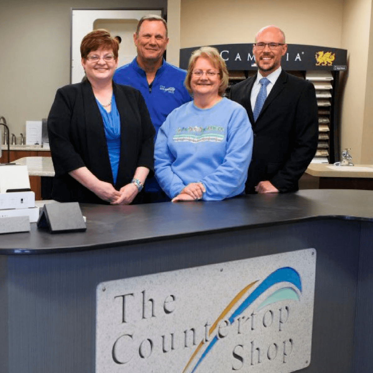 Four staff members smiling behind the front desk of The Countertop Shop showroom