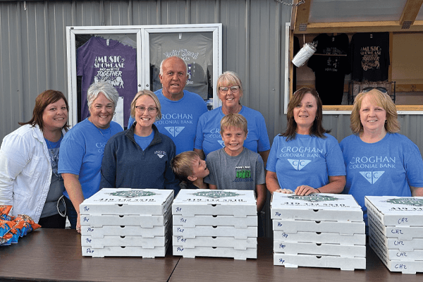 Croghan Colonial Bank volunteers posing with stacked pizza boxes at a community fundraiser event
