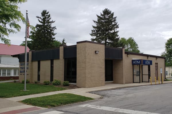 Croghan Colonial Bank branch exterior with ATM vestibule, brick facade, and flagpole on a cloudy day