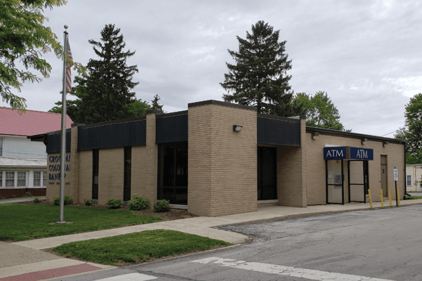 Croghan Colonial Bank branch exterior with ATM vestibule, brick facade, and flagpole on a cloudy day