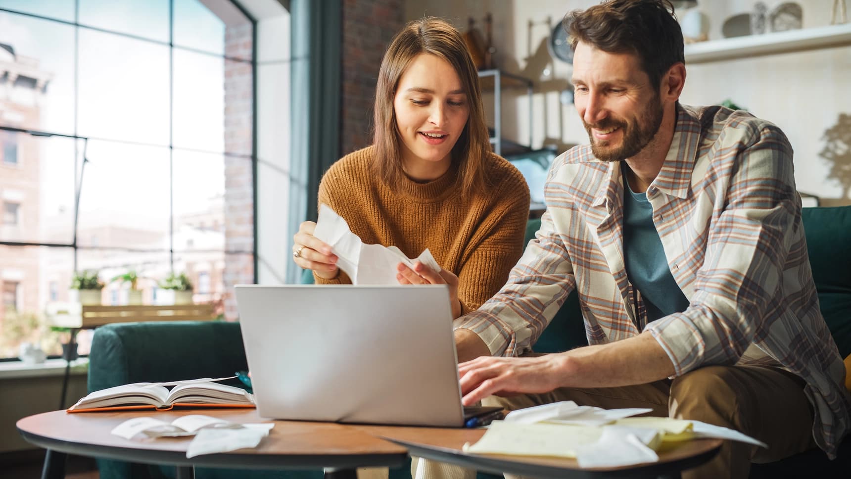 Couple reviewing receipts and managing finances together on a laptop at home