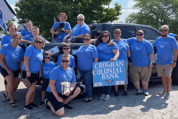 Croghan Colonial Bank team in blue branded shirts posing together at an outdoor community event