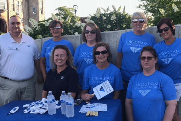 Croghan Colonial Bank team in blue shirts at an outdoor community event registration table