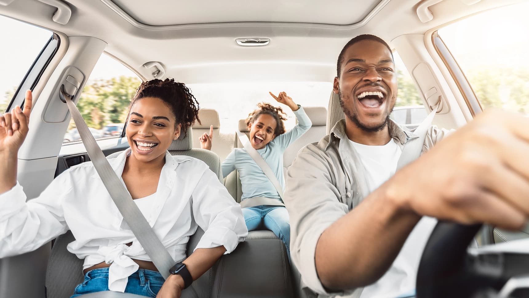 Happy family laughing and dancing while riding together in a car with seatbelts on