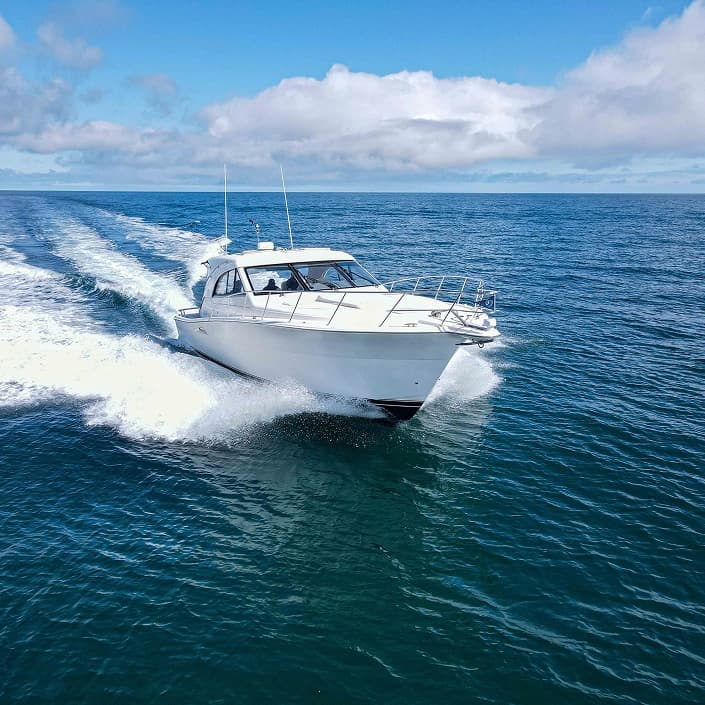 White motorboat speeding across open blue ocean water under a partly cloudy sky