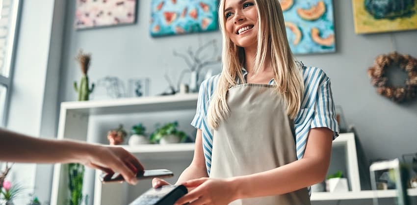 Smiling shop owner processing a contactless mobile payment at her store