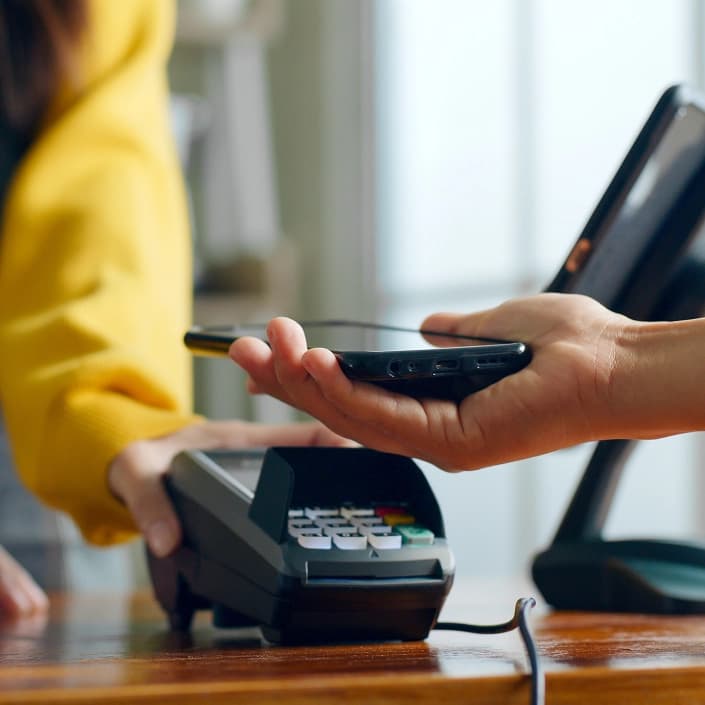 Customer tapping a smartphone on a payment terminal for contactless checkout