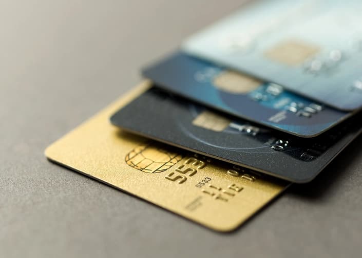 Stack of gold, black, and blue credit and debit cards on a gray surface