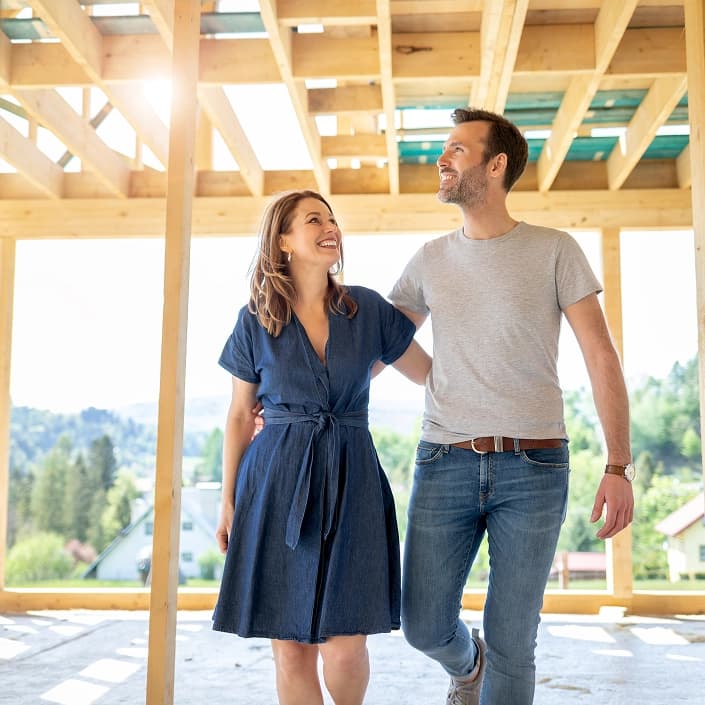 A happy couple smiling at each other inside a home under construction