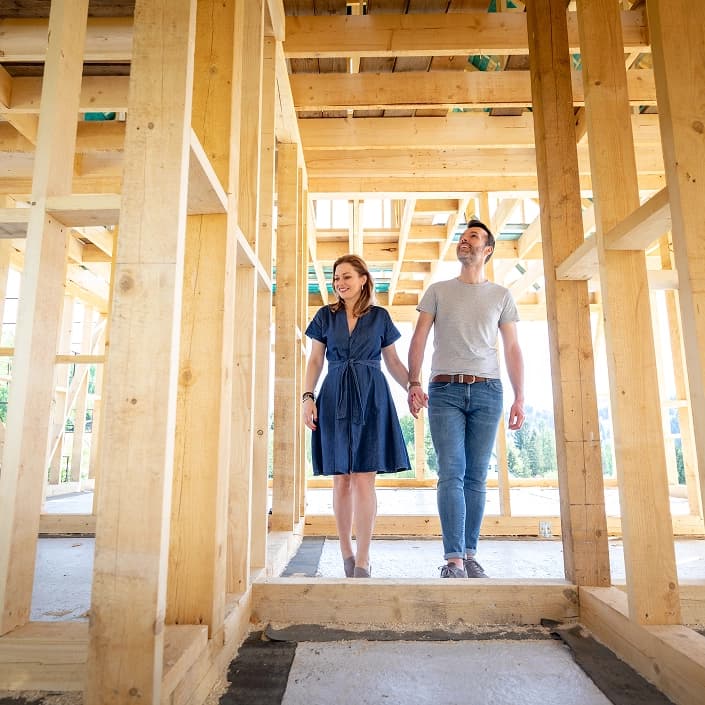 Couple holding hands while touring the framed interior of their new home under construction