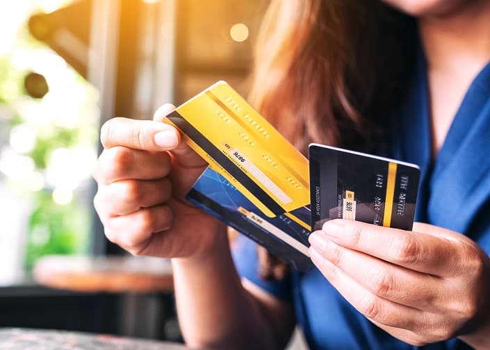 Person holding multiple credit and debit cards, choosing a payment option